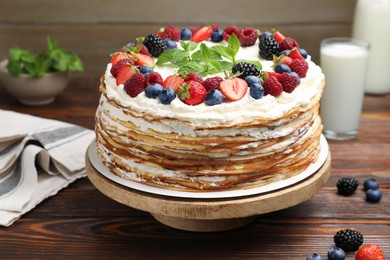 Photo of Delicious crepe cake with fresh berries on wooden table, closeup