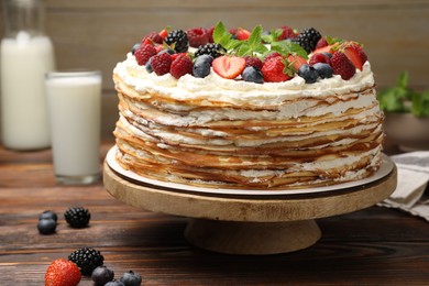 Photo of Delicious crepe cake with fresh berries on wooden table, closeup
