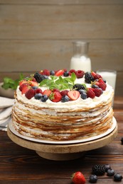 Photo of Delicious crepe cake with fresh berries on wooden table, closeup