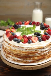 Photo of Delicious crepe cake with fresh berries on wooden table, closeup
