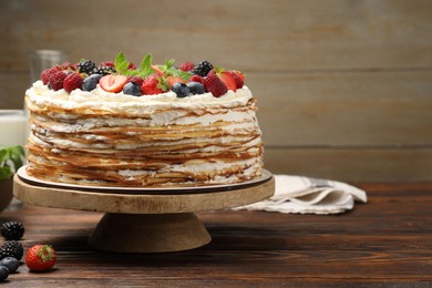 Photo of Delicious crepe cake with fresh berries on wooden table. Space for text