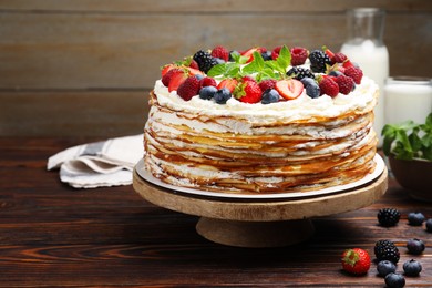 Photo of Delicious crepe cake with fresh berries on wooden table