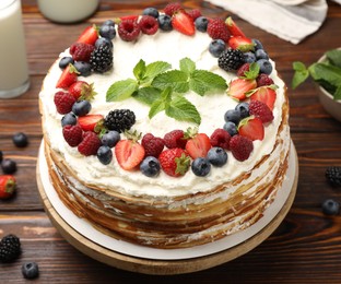 Photo of Delicious crepe cake with fresh berries on wooden table, closeup