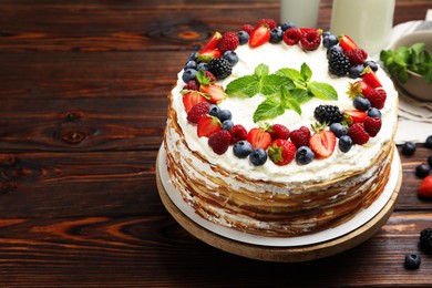 Photo of Delicious crepe cake with fresh berries on wooden table, closeup. Space for text