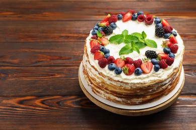 Photo of Delicious crepe cake with fresh berries on wooden table, closeup. Space for text