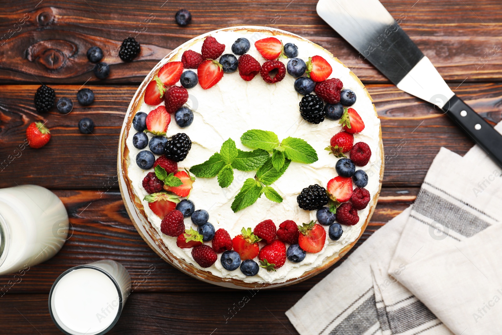 Photo of Delicious crepe cake with fresh berries served on wooden table, flat lay