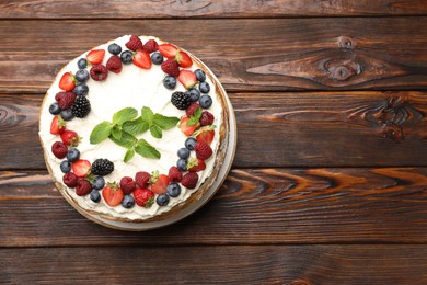 Photo of Delicious crepe cake with fresh berries on wooden table, top view. Space for text