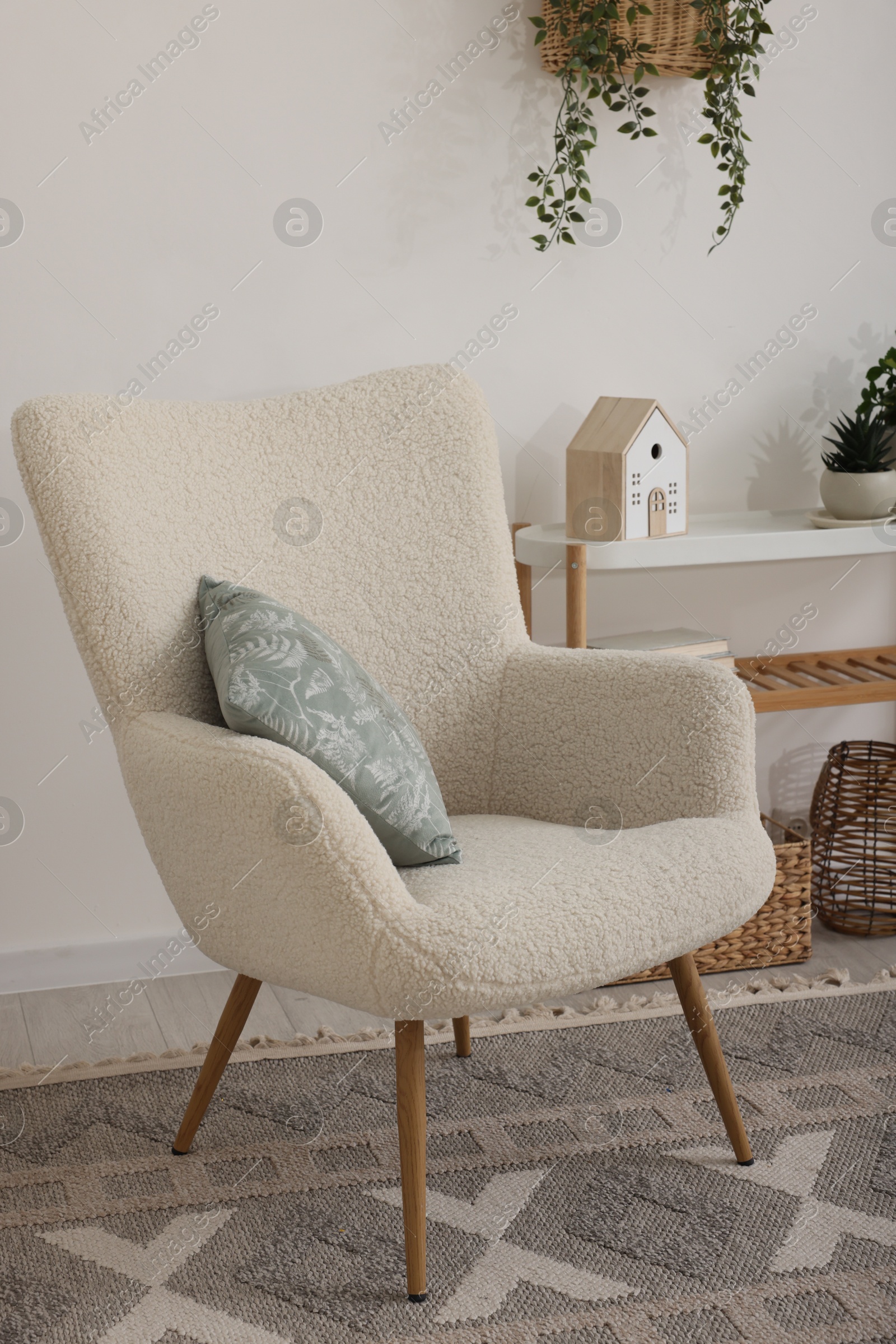 Photo of Stylish armchair, console table and decor in room. Interior design