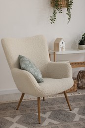 Photo of Stylish armchair, console table and decor in room. Interior design