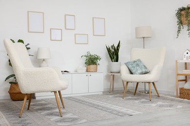 Photo of Stylish armchairs, cabinet and houseplants in room. Interior design