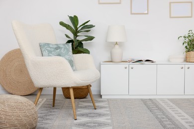 Photo of Stylish armchair, cabinet and houseplants in room. Interior design