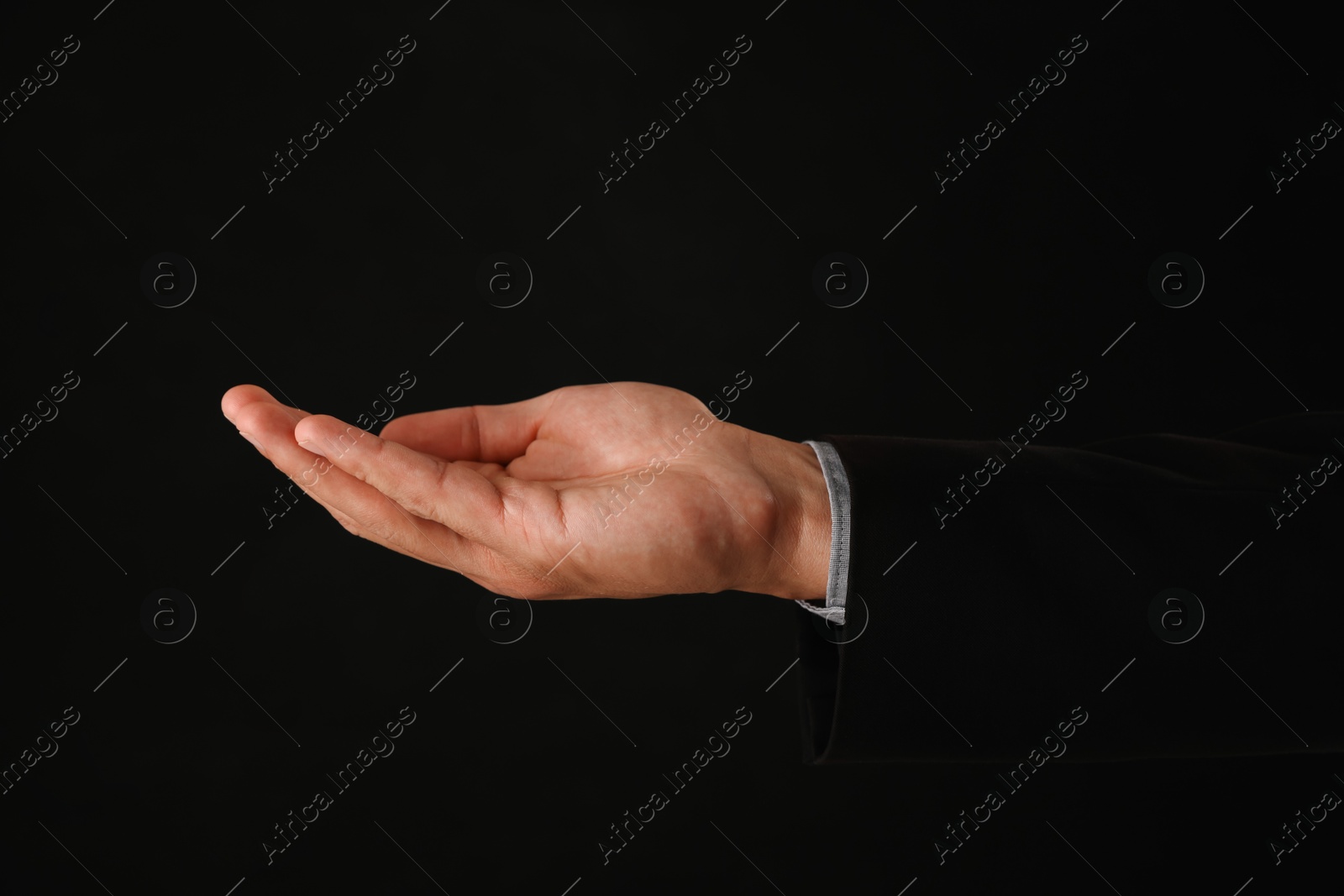 Man holding something on black background, closeup Photo of Man holding something on black background, closeup