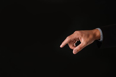Photo of Man touching something on black background, closeup. Space for text