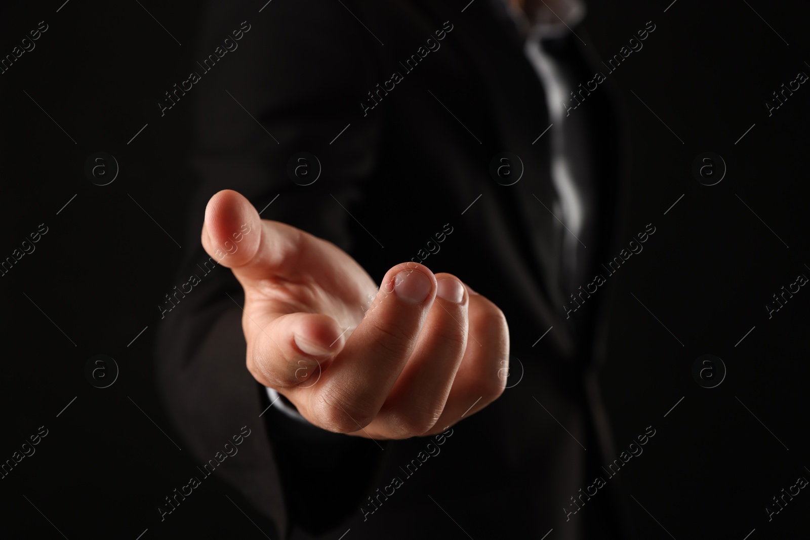 Man holding something on black background, closeup Photo of Man holding something on black background, closeup