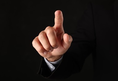 Photo of Man touching something on black background, closeup