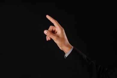 Photo of Man touching something on black background, closeup. Space for text