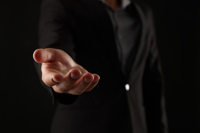 Photo of Man holding something on black background, closeup