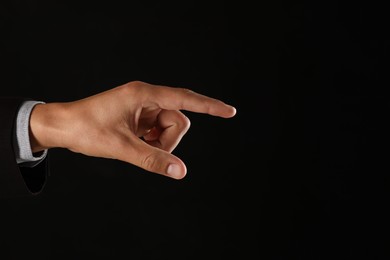 Photo of Man touching something on black background, closeup. Space for text