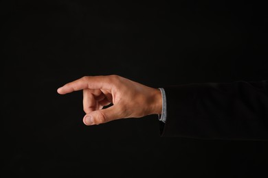 Photo of Man touching something on black background, closeup