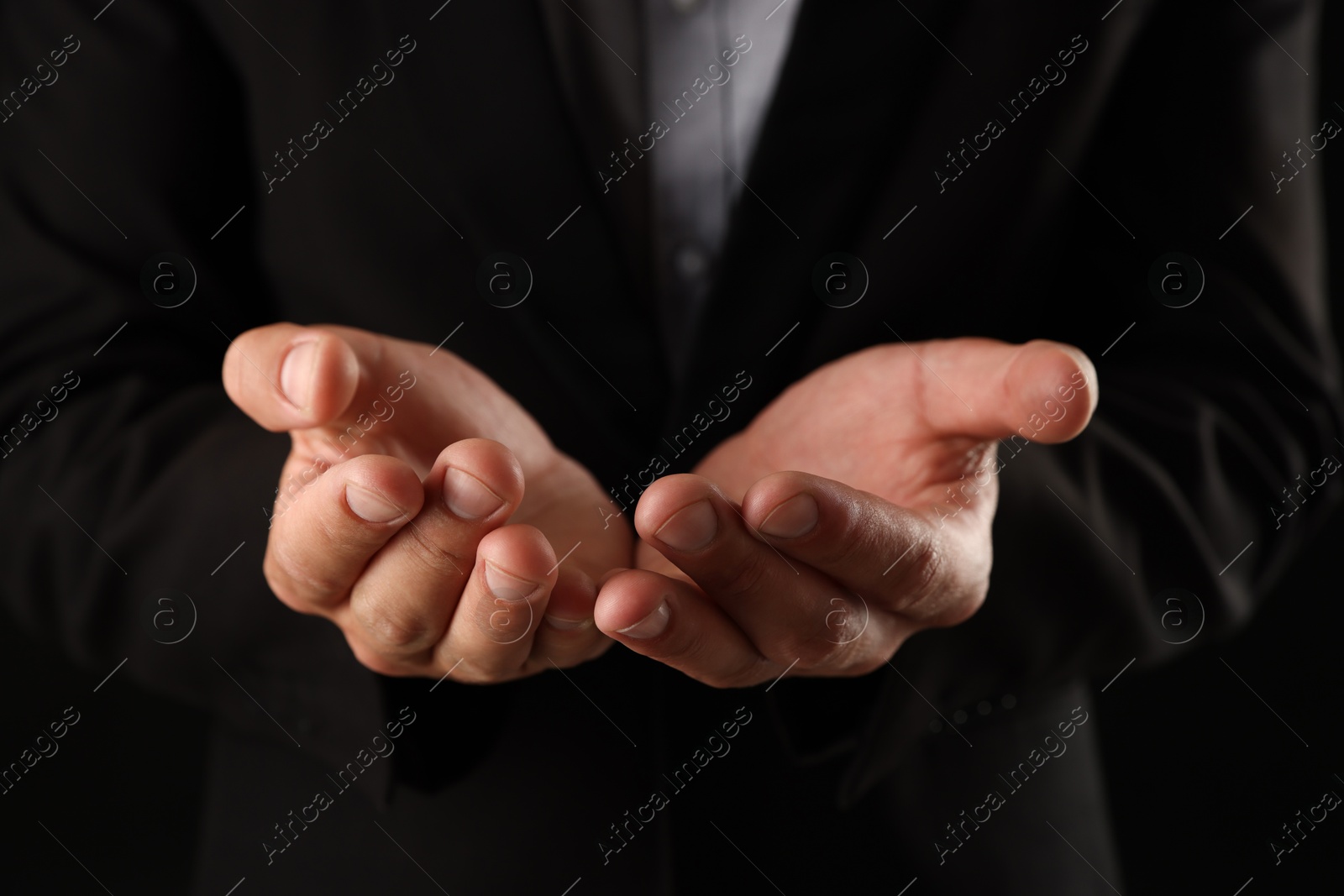 Man holding something on black background, closeup Photo of Man holding something on black background, closeup