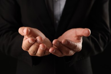 Photo of Man holding something on black background, closeup