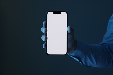 Photo of Man with modern smartphone on dark background, closeup. Mockup for design