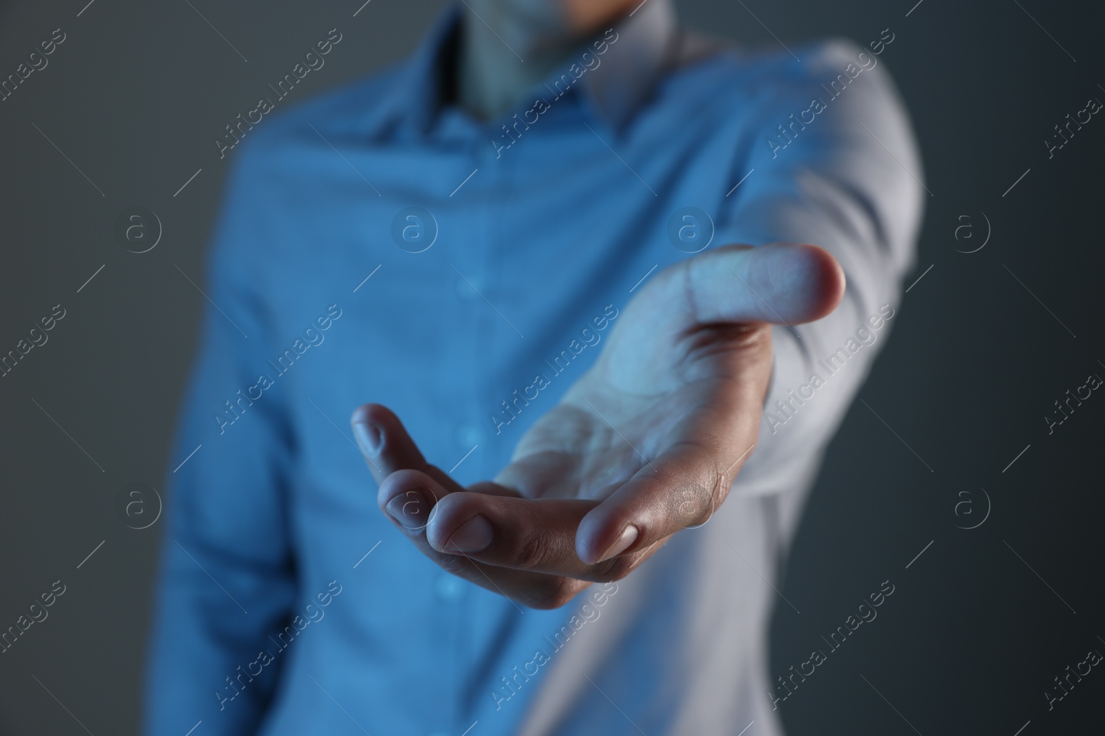 Man holding something on grey background, closeup Photo of Man holding something on grey background, closeup