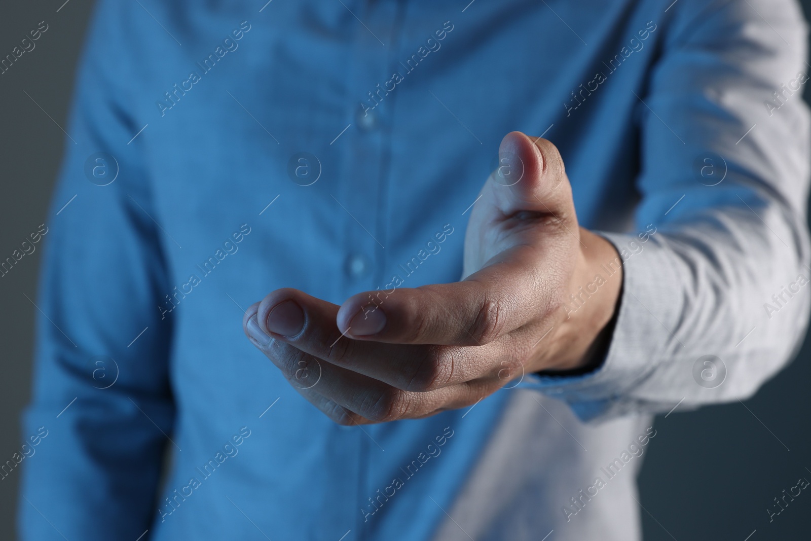 Man holding something on grey background, closeup Photo of Man holding something on grey background, closeup