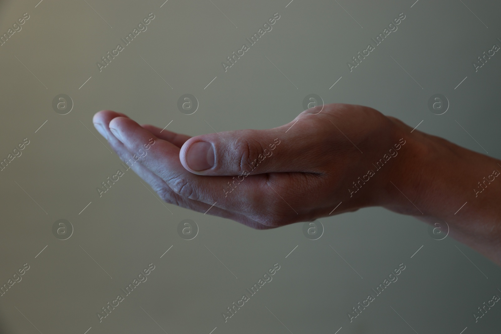 Man holding something on grey background, closeup Photo of Man holding something on grey background, closeup