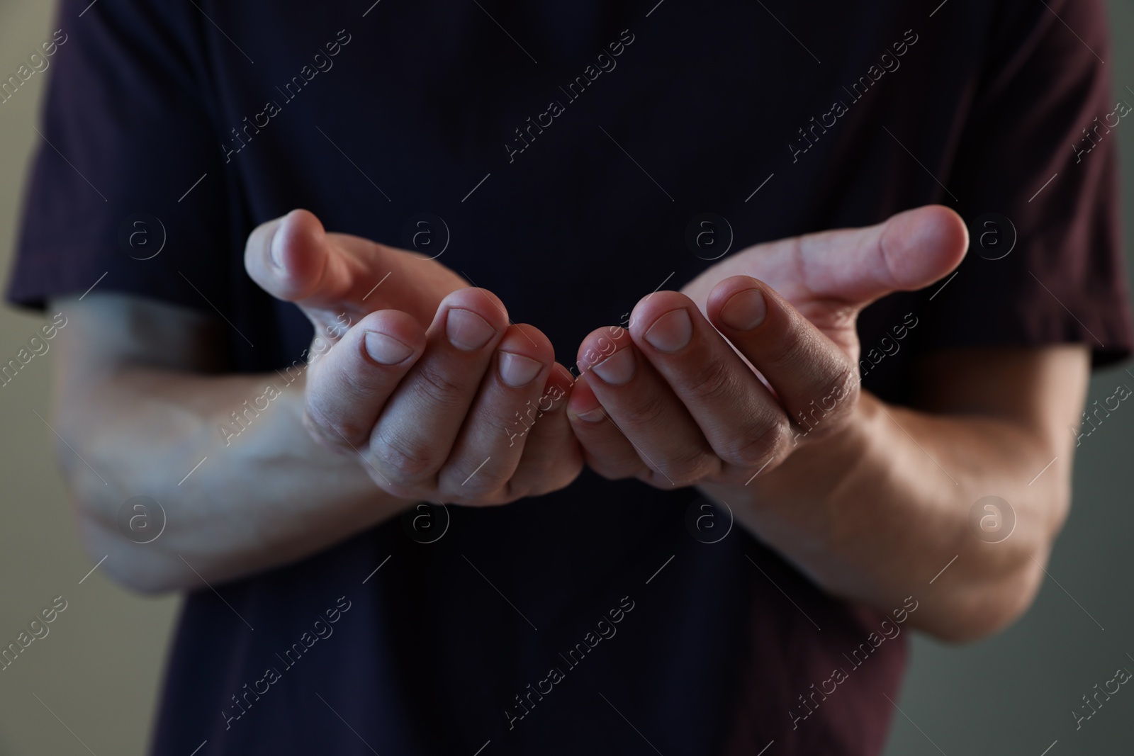Man holding something on grey background, closeup Photo of Man holding something on grey background, closeup