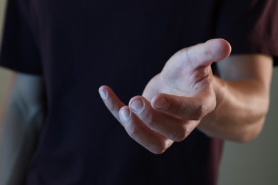 Photo of Man holding something on grey background, closeup