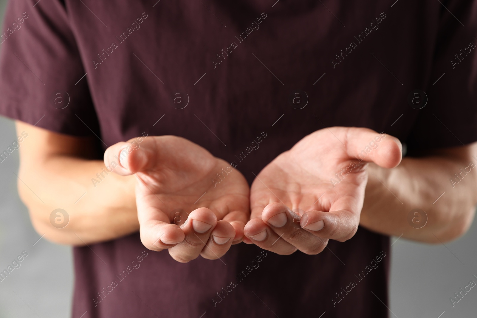 Man holding something on grey background, closeup Photo of Man holding something on grey background, closeup