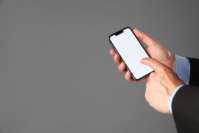 Photo of Man with modern smartphone on grey background, closeup. Mockup for design