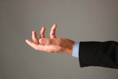 Photo of Man holding something on grey background, closeup