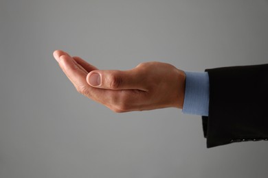 Photo of Man holding something on grey background, closeup