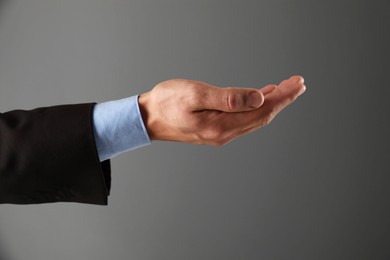 Photo of Man holding something on grey background, closeup