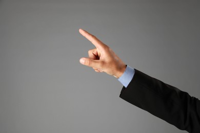 Photo of Man touching something on grey background, closeup. Space for text