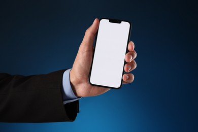 Photo of Man with modern smartphone on blue background, closeup. Mockup for design