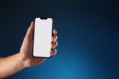 Photo of Man with modern smartphone on blue background, closeup. Mockup for design