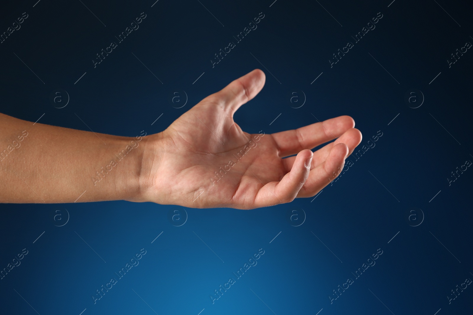 Man holding something on blue background, closeup Photo of Man holding something on blue background, closeup