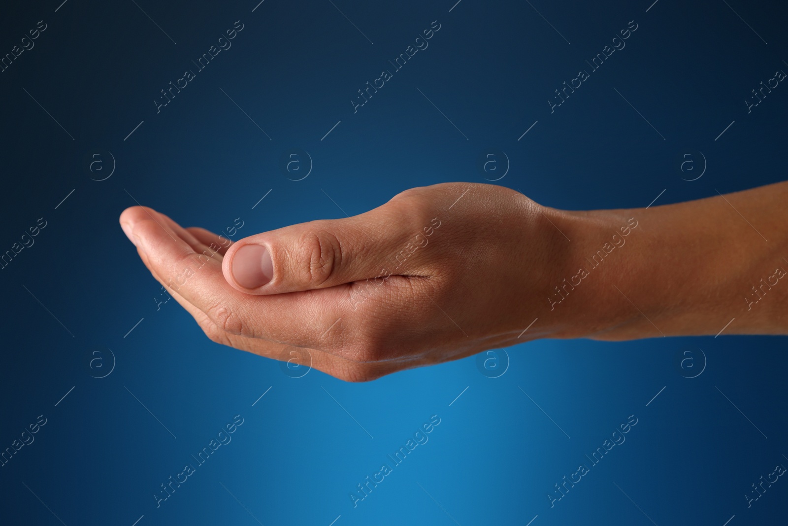 Man holding something on blue background, closeup Photo of Man holding something on blue background, closeup