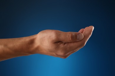 Photo of Man holding something on blue background, closeup