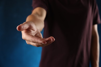 Photo of Man holding something on blue background, closeup