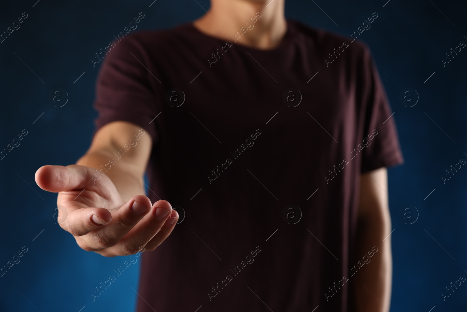 Man holding something on blue background, closeup Photo of Man holding something on blue background, closeup