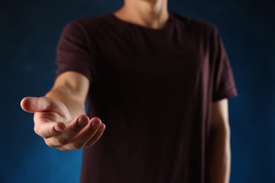 Photo of Man holding something on blue background, closeup