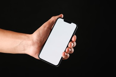 Photo of Man with modern smartphone on black background, closeup. Mockup for design