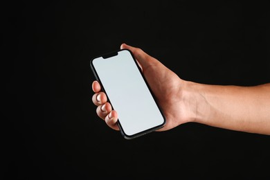 Photo of Man with modern smartphone on black background, closeup. Mockup for design