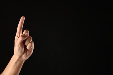Photo of Man touching something on black background, closeup. Space for text