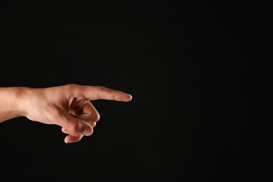 Photo of Man touching something on black background, closeup. Space for text