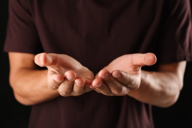 Photo of Man holding something on black background, closeup